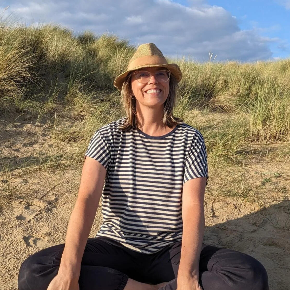 Smiling woman in a hat on a sand dune.